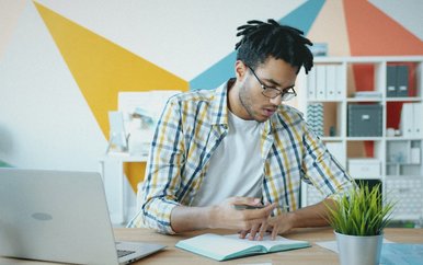 Young man working on a laptop at a desk in a colorful room