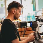 Barista frothing milk behind the café counter