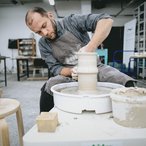 Potter shaping a vase on a wheel in his studio